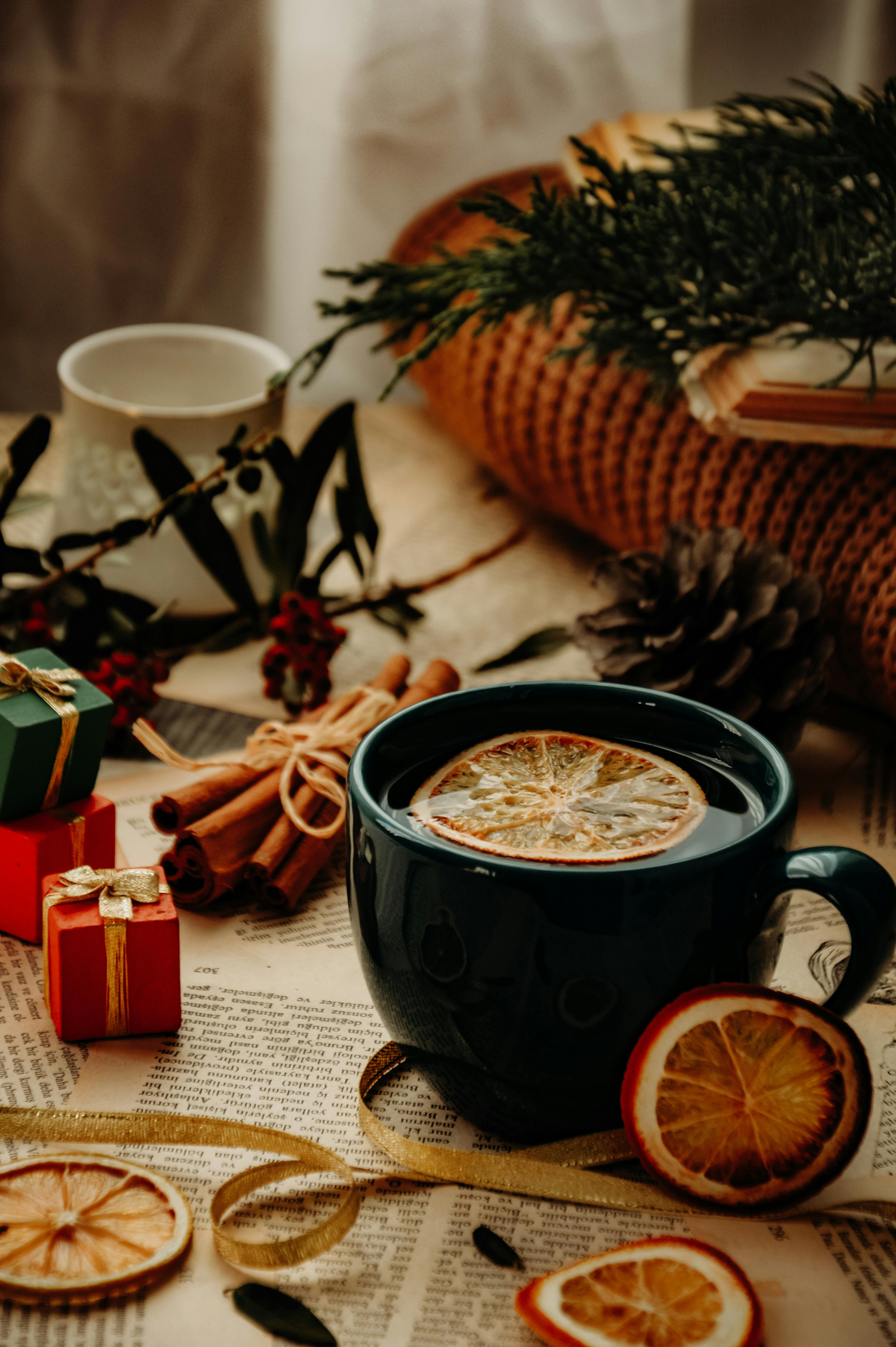 Warm Christmas scene with tea, cinnamon sticks, dried oranges, and wrapped gifts.