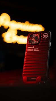 Close-up of a modern smartphone with a red designer hard case, glowing bokeh background.