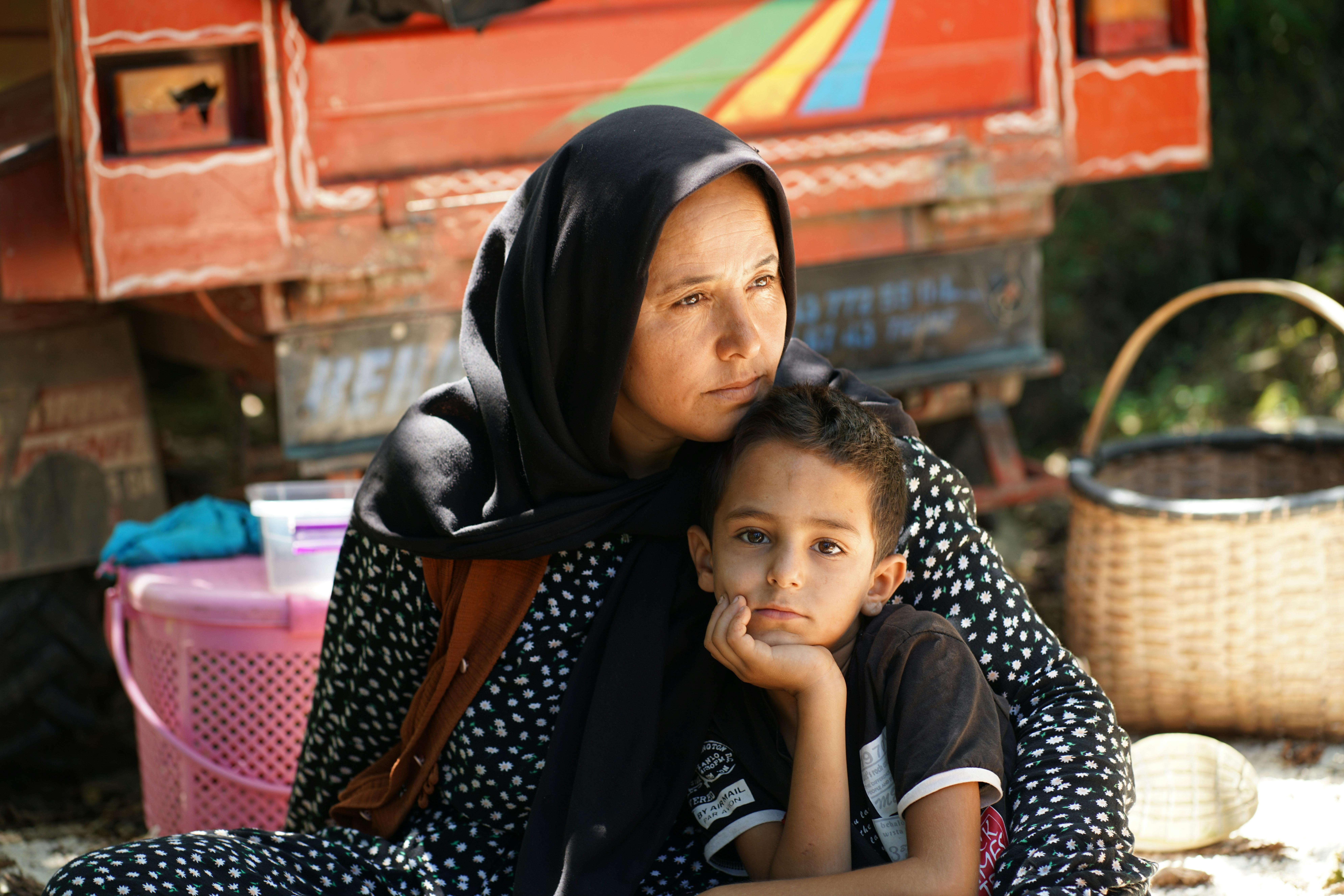 A mother and her son embracing affectionately while sitting outdoors, reflecting warmth and connection.