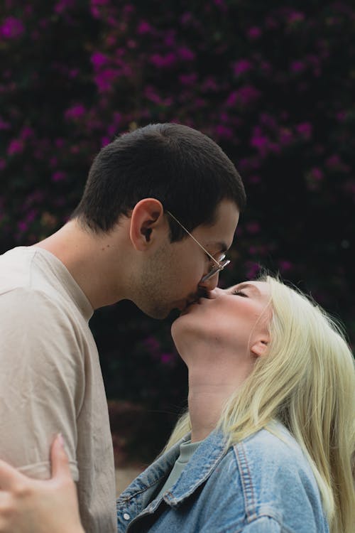 Free A loving couple shares an intimate kiss surrounded by lush garden flora. Stock Photo