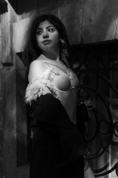 Black and white portrait of a woman in lingerie, posing elegantly in shadows against urban architecture