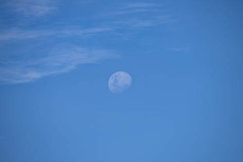A blue sky with a white moon in the middle