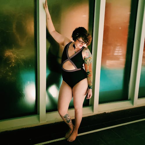 Woman in Swimsuit Posing next to Indoor Swimming Pool at Night