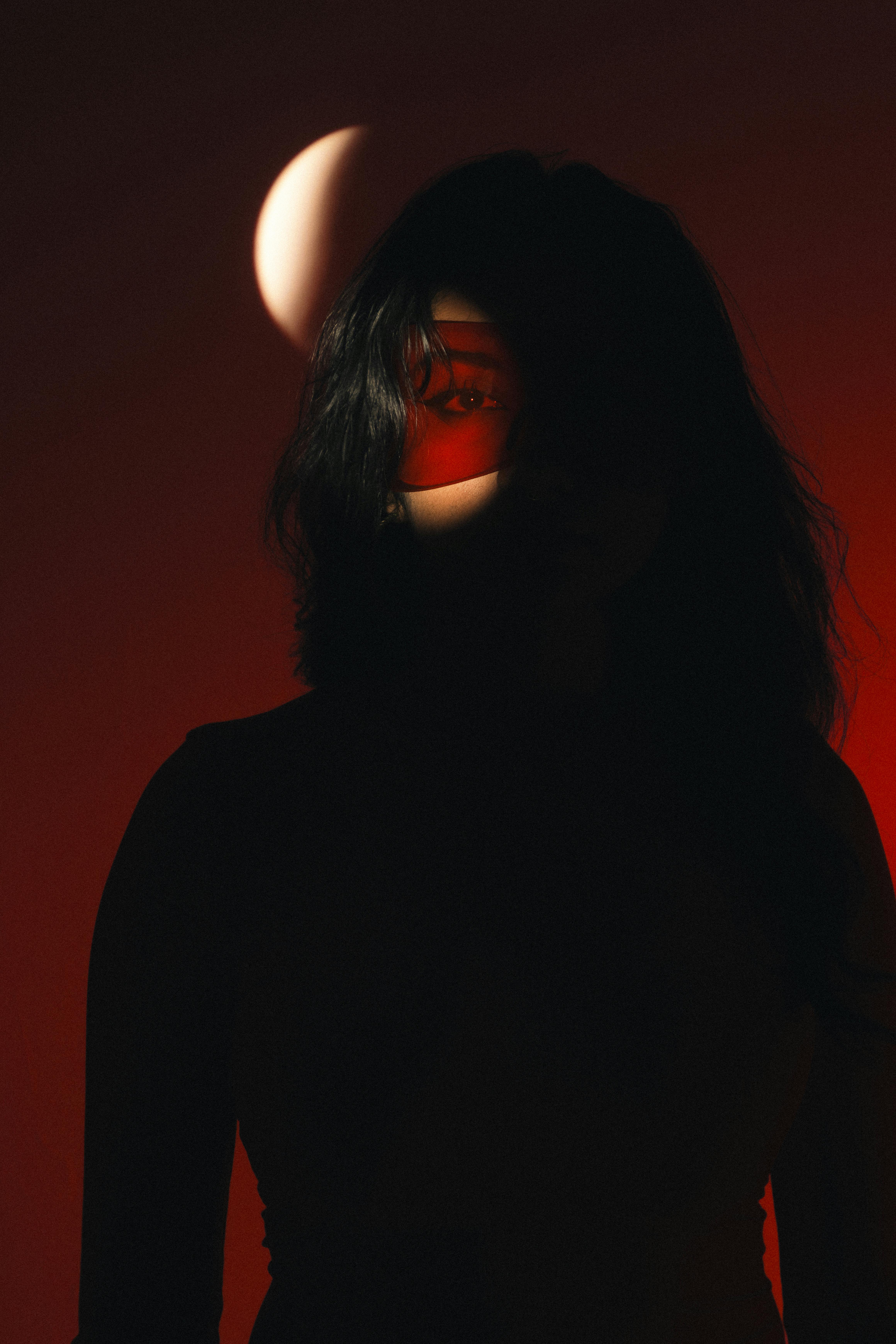A dramatic silhouette of a woman with red lighting and shadow play on her face, creating an enigmatic portrait.