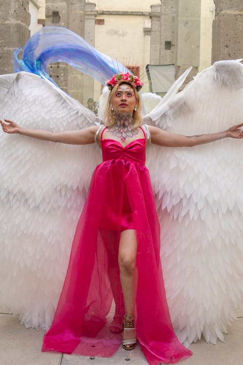 A woman in a pink dress and wings posing for a photo