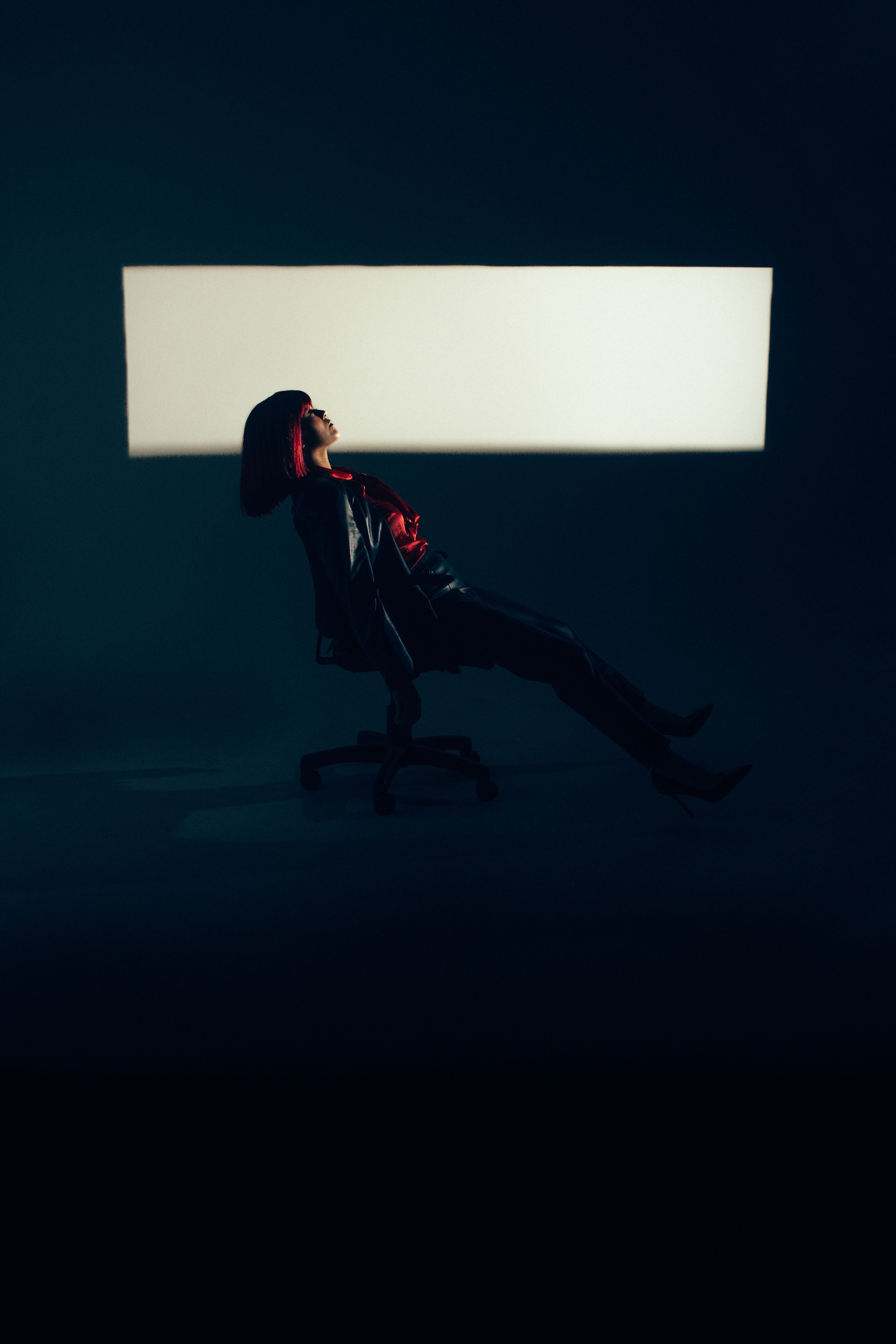 Woman Lying on an Office Chair in a Dark Room · Free Stock Photo