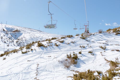 A ski lift is on a snowy hill with snow