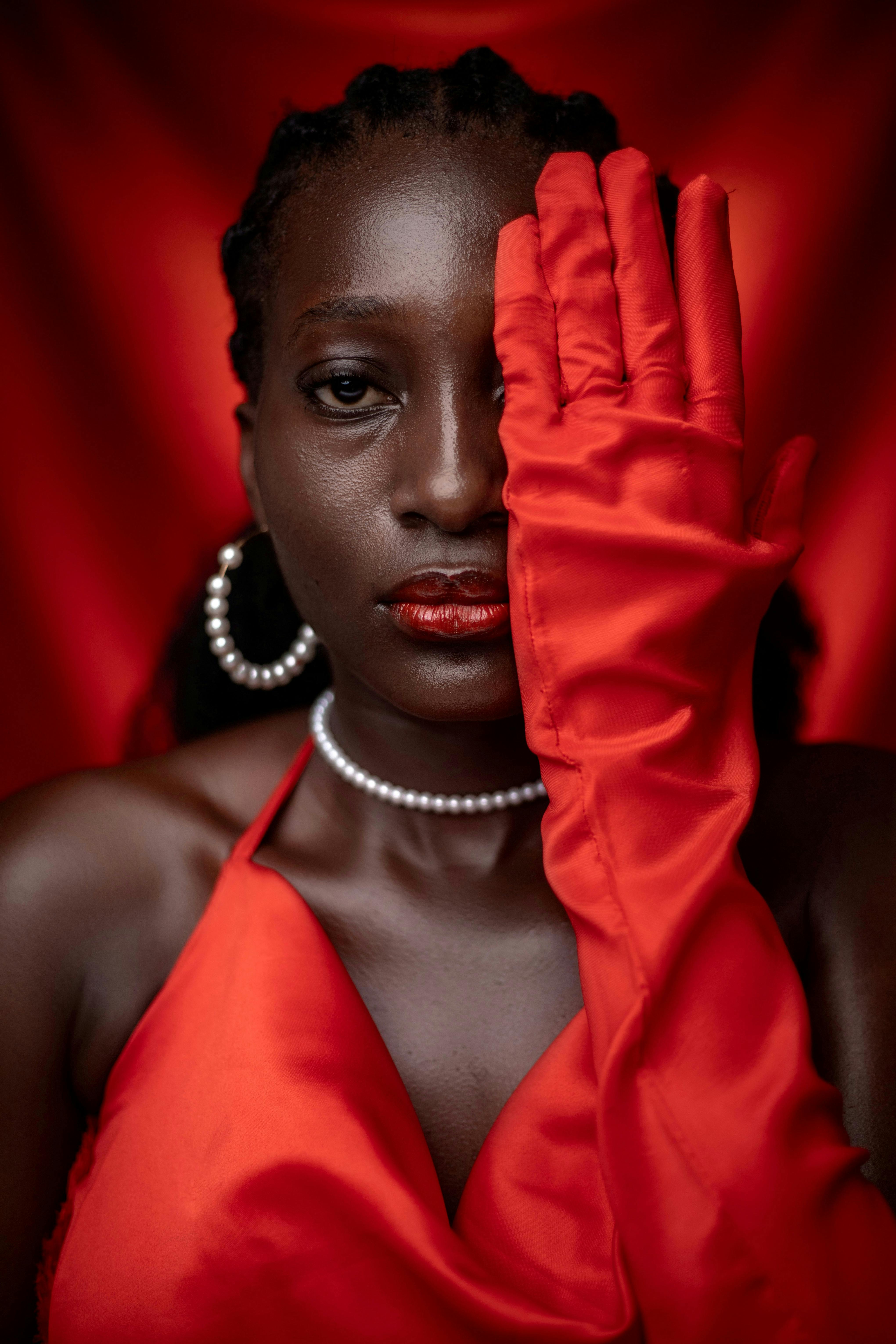 Stylish portrait of a woman in a red dress with pearls in a studio shoot.