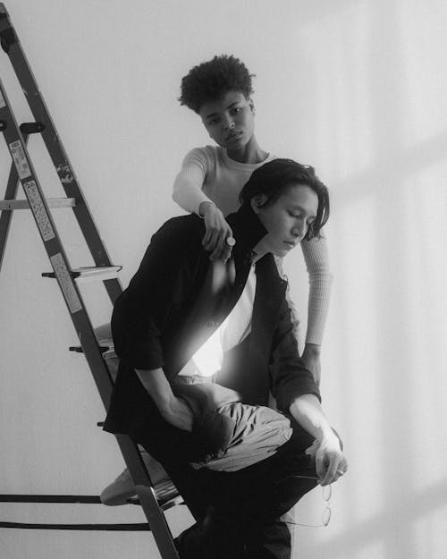 A black and white photo of two people on a ladder