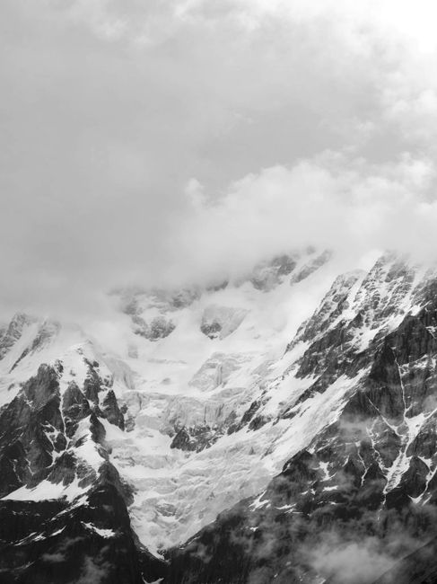 Majestic snow-covered mountain peaks shrouded in clouds, capturing the essence of Kedarnath's winter landscape.