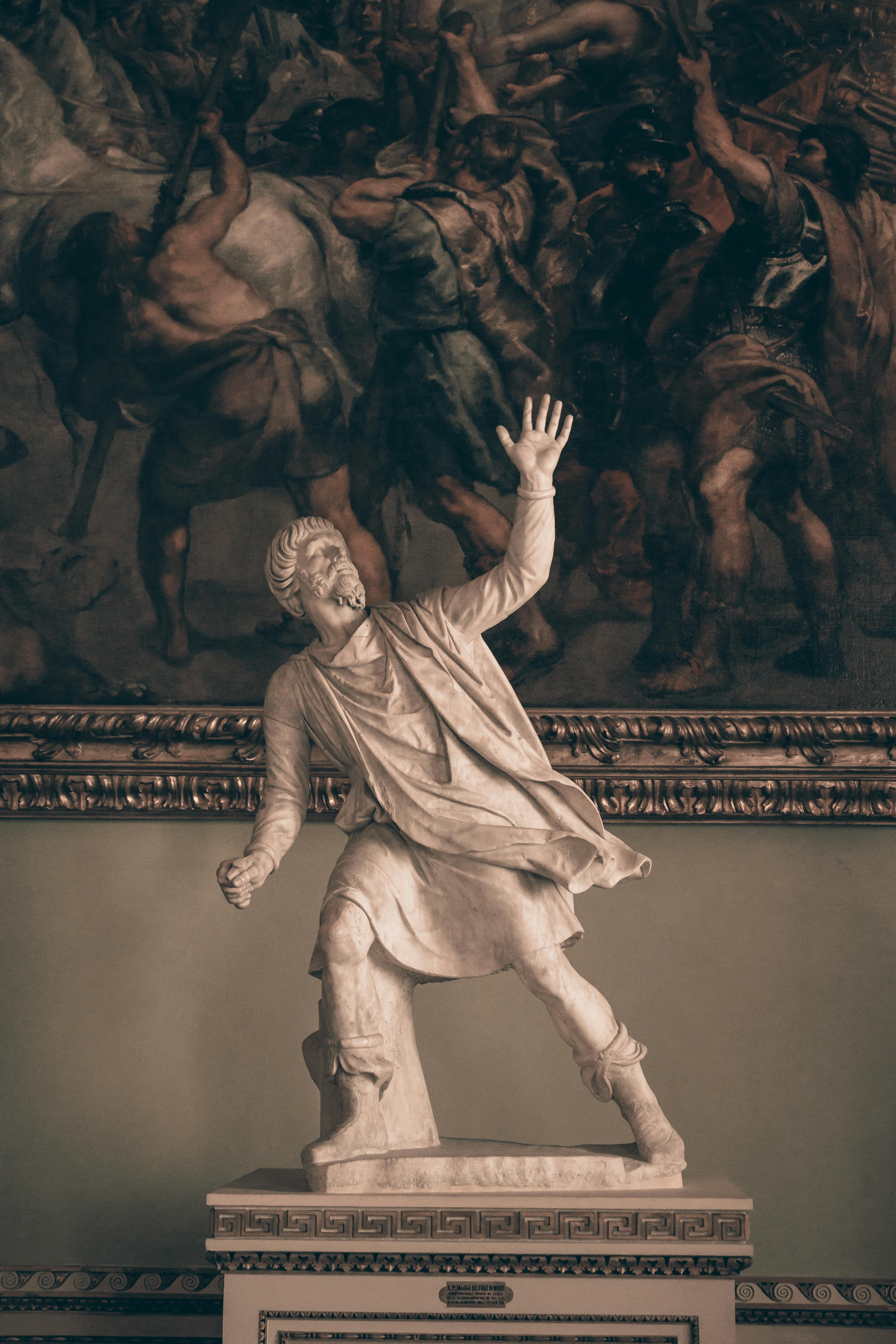 Elegant marble sculpture in Florence museum against a rich historical painting.