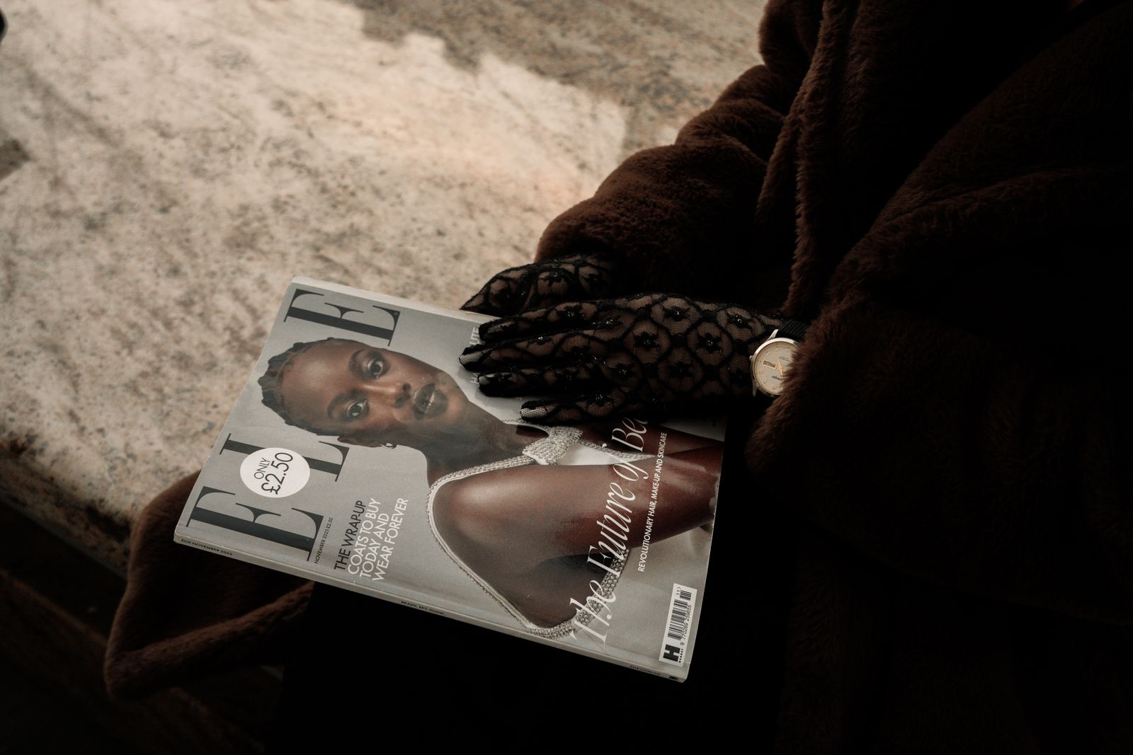 Woman holding fashion magazine with gloved hands