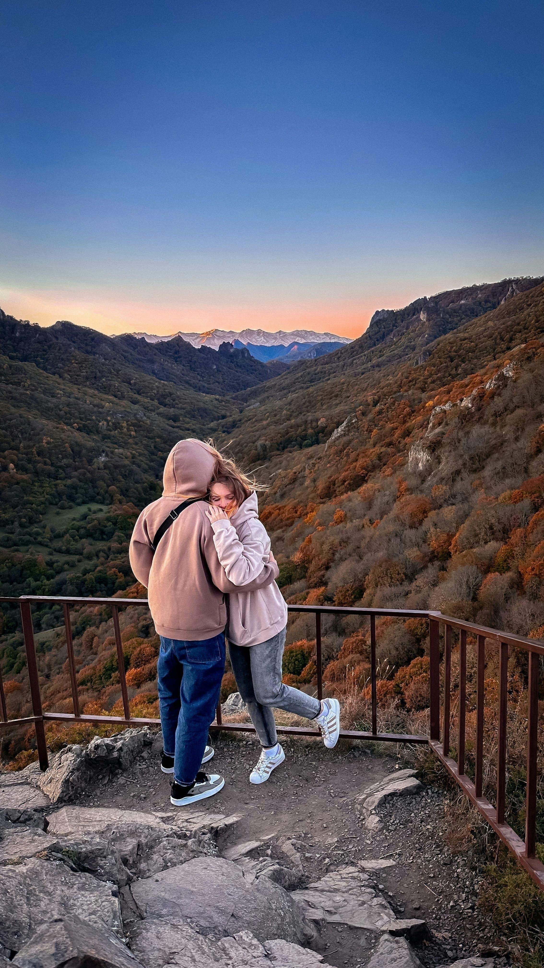 Couple hugging at sunset with breathtaking mountain landscape view.