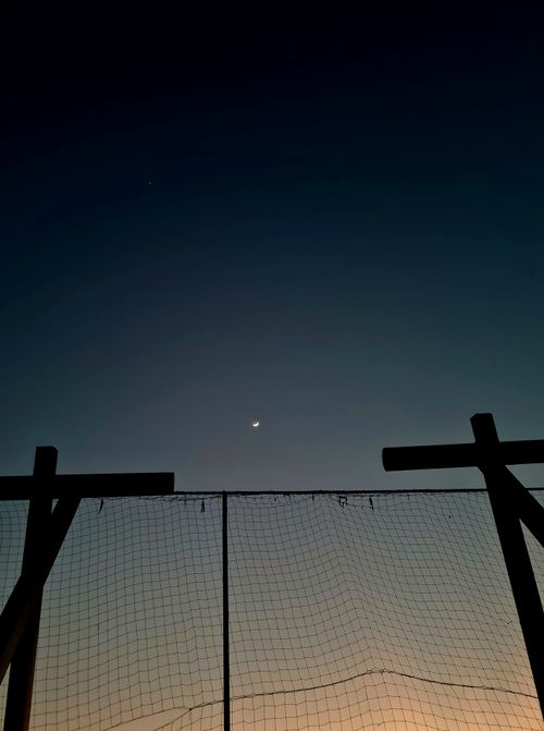 Free Crescent moon and star visible above a wooden fence during nighttime, serene sky. Stock Photo