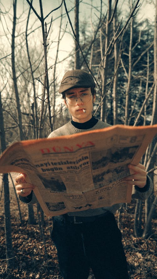 A man holding a newspaper in the woods