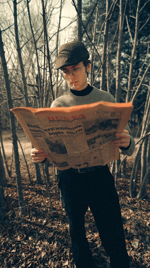 A man reading a newspaper in the woods