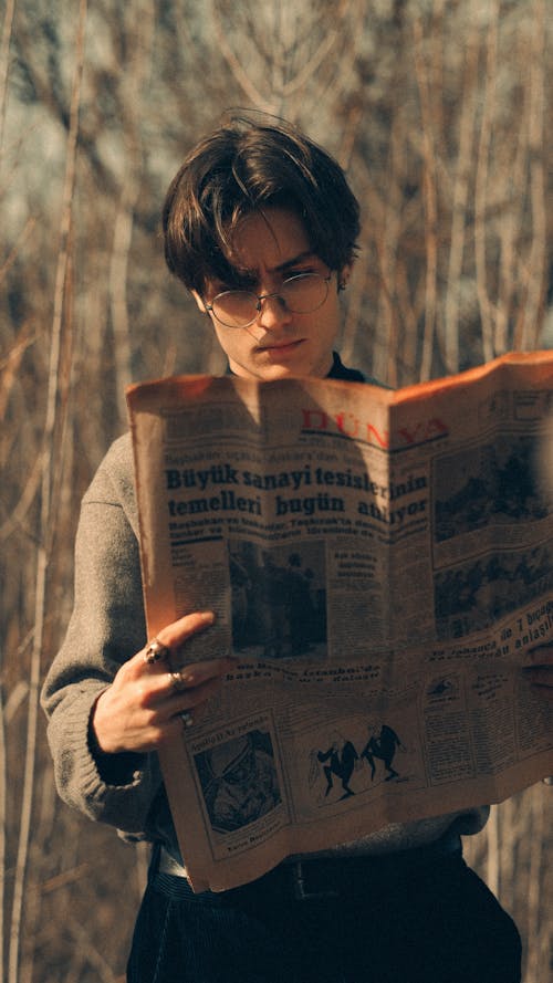 A man reading a newspaper in the woods