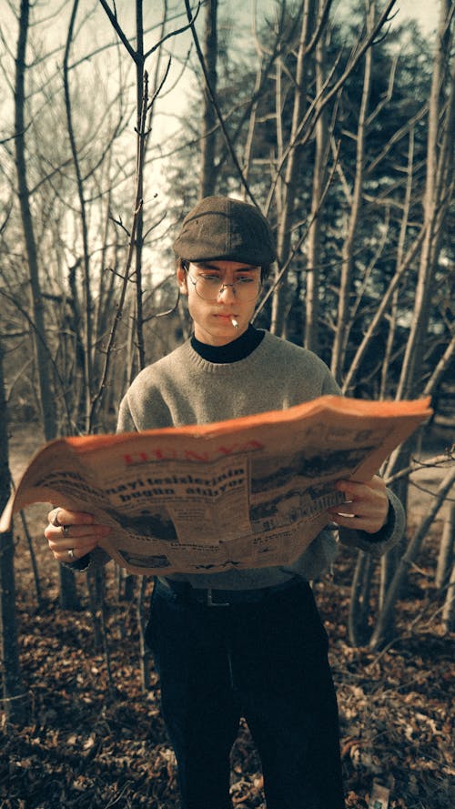 A man in a hat and glasses holding a newspaper