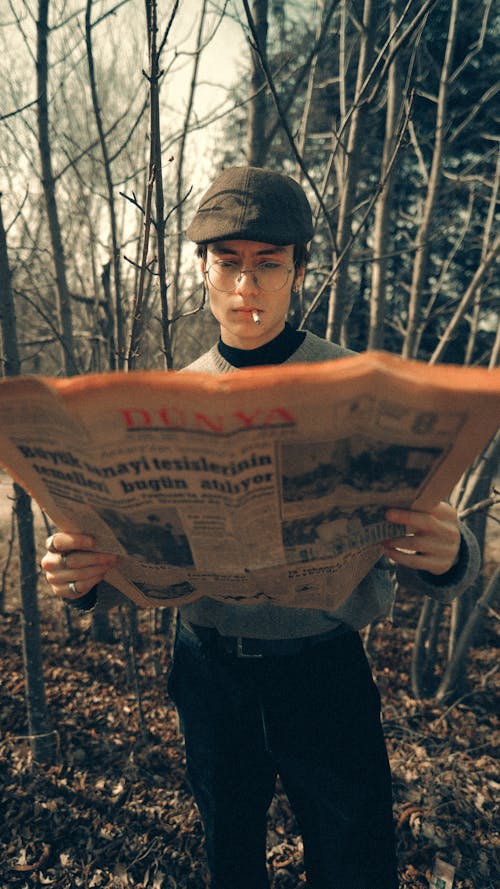 A man reading a newspaper in the woods