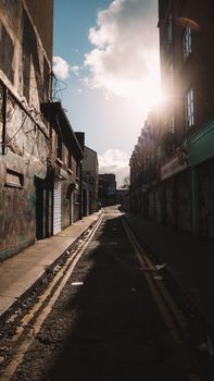 Sunlit street scene in a quiet urban alley at sunset with dramatic shadows.