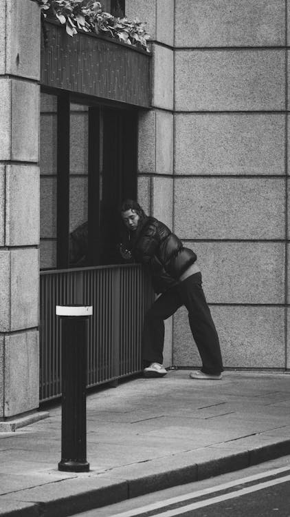 Woman in Jacket Leaning on Railing on Sidewalk