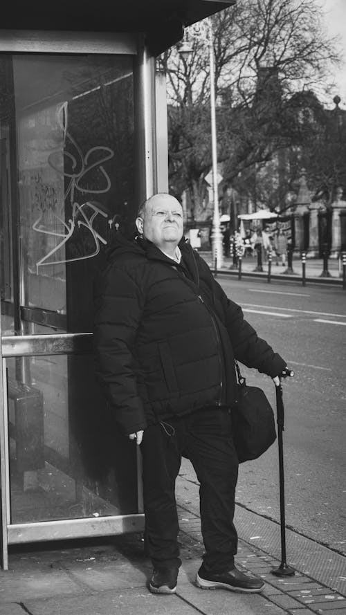 A man standing outside a bus stop with a cane