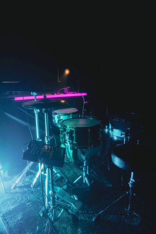 Free An illuminated drum set on a dark stage with colorful lights, capturing a concert atmosphere. Stock Photo