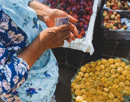 A woman holding money at a vibrant fruit market in Samarkand, Uzbekistan.