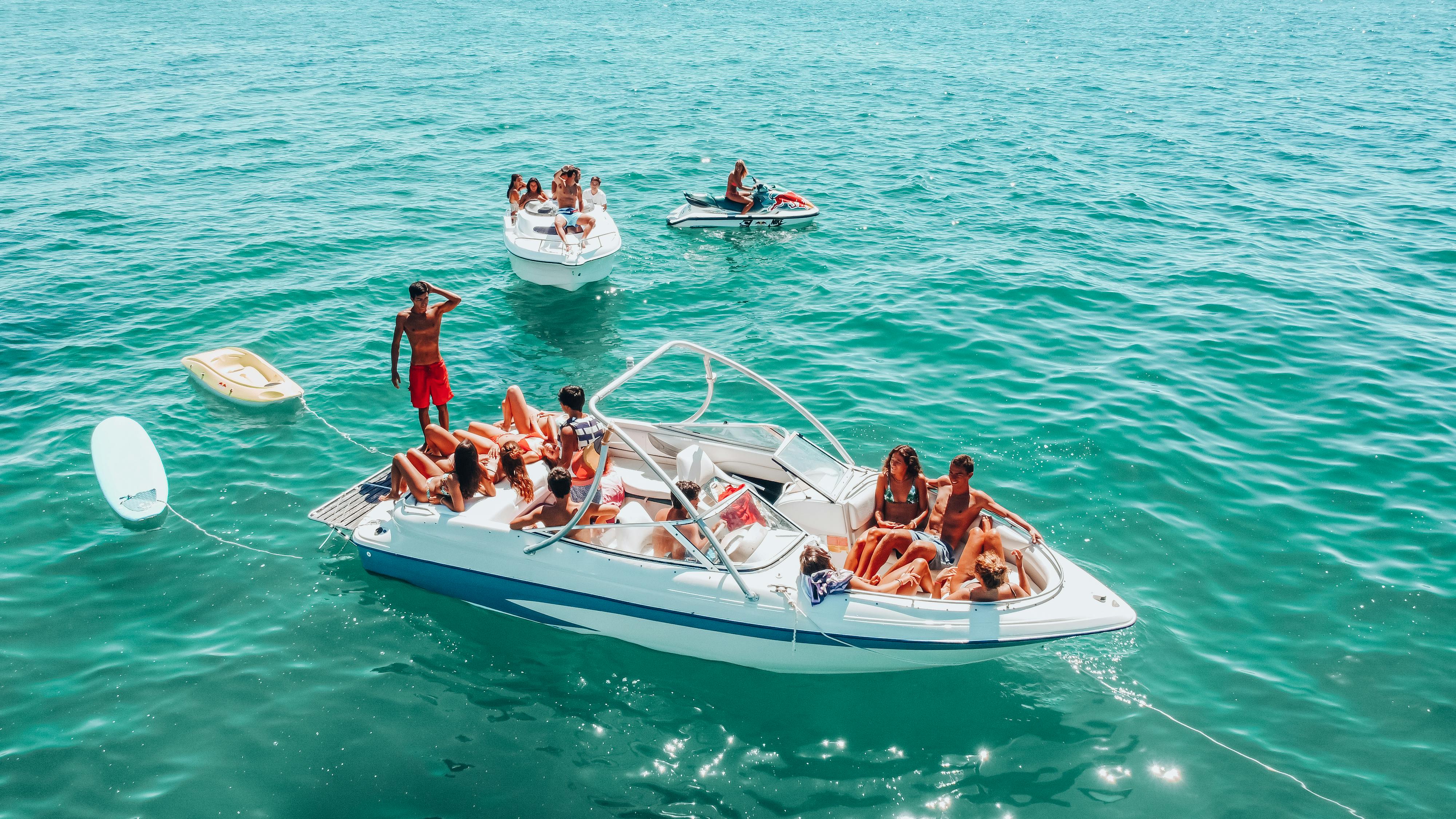 A group enjoying a sunny day on motorboats in Armação de Pêra, Portugal.