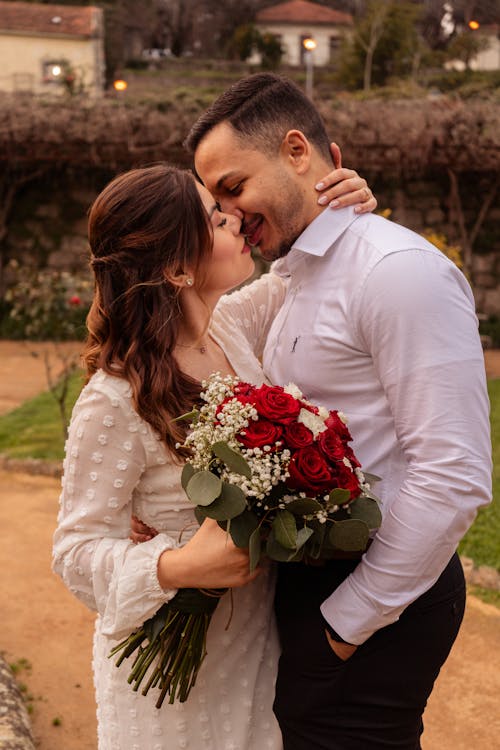 A couple kissing in front of a stone wall