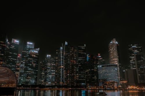 Free A breathtaking view of Singapore's illuminated skyline reflecting on water, captured at night. Stock Photo