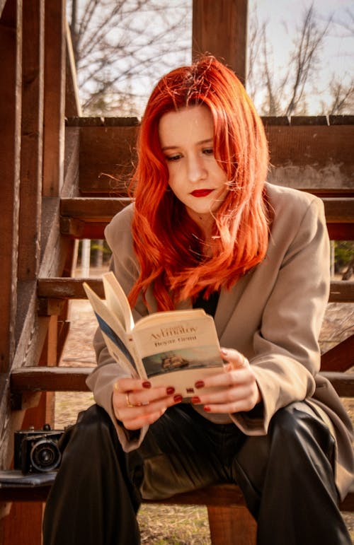 Close Up of a Redhead Sitting On the Stairs with a Book 