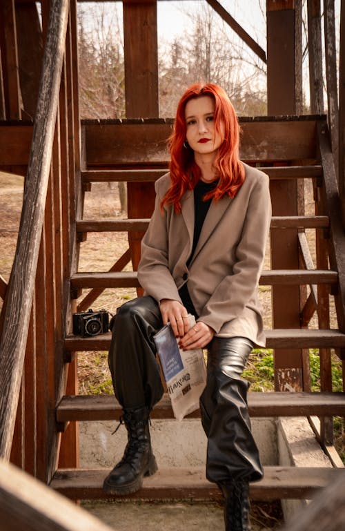 A woman with red hair sitting on some stairs