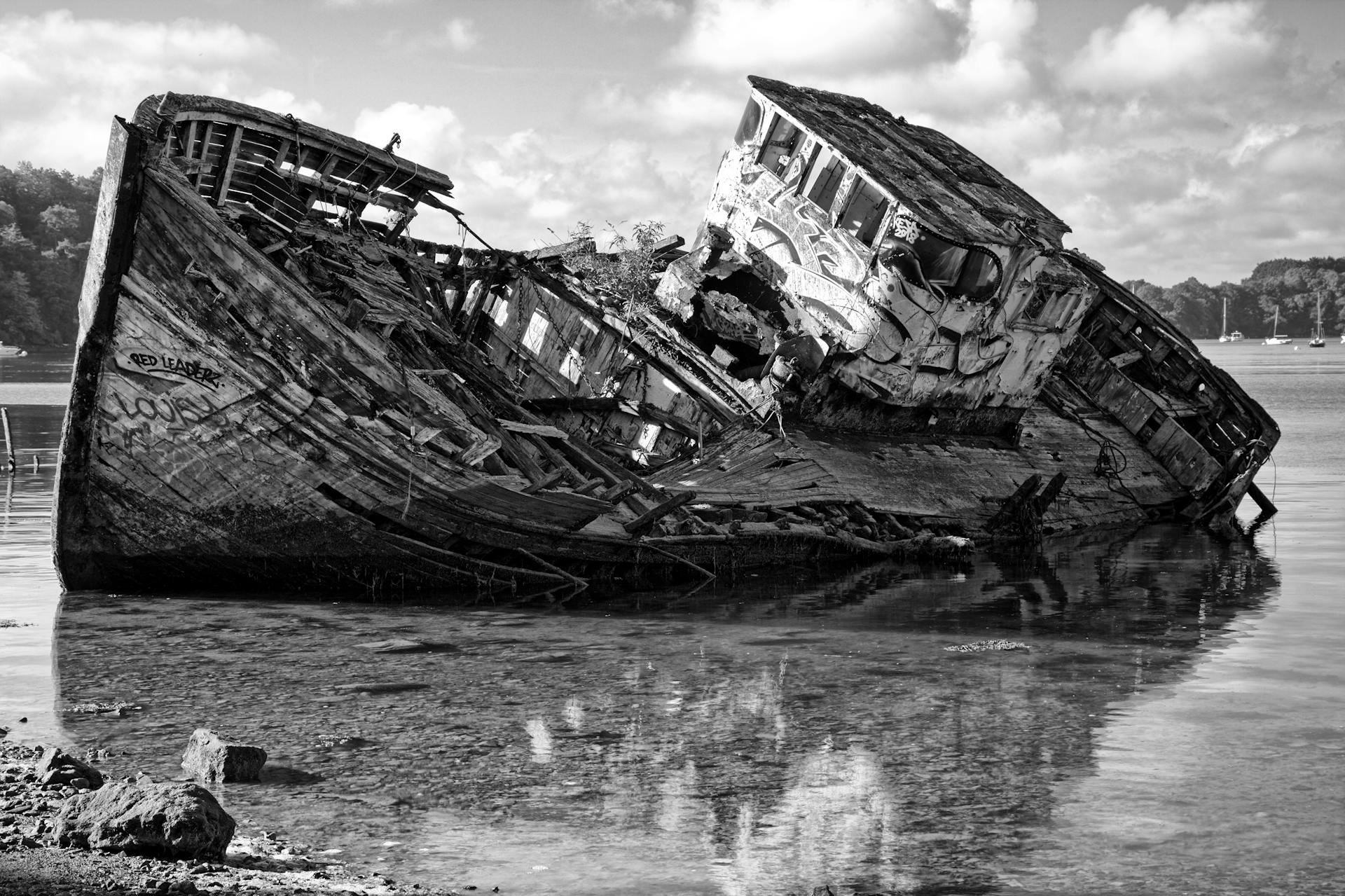 Black and white photo of a decaying shipwreck on the shore of Saint-Malo, France.