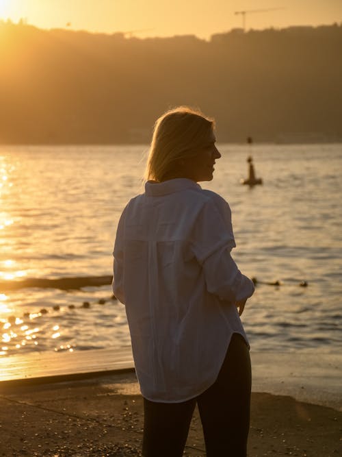 Blonde Woman in White Shirt on Sea Shore at Sunset