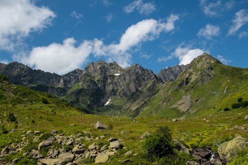A mountain range with grass and rocks under a blue sky