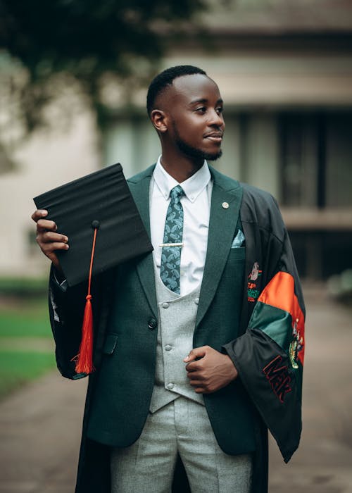 A young man in a suit and tie holding a diploma