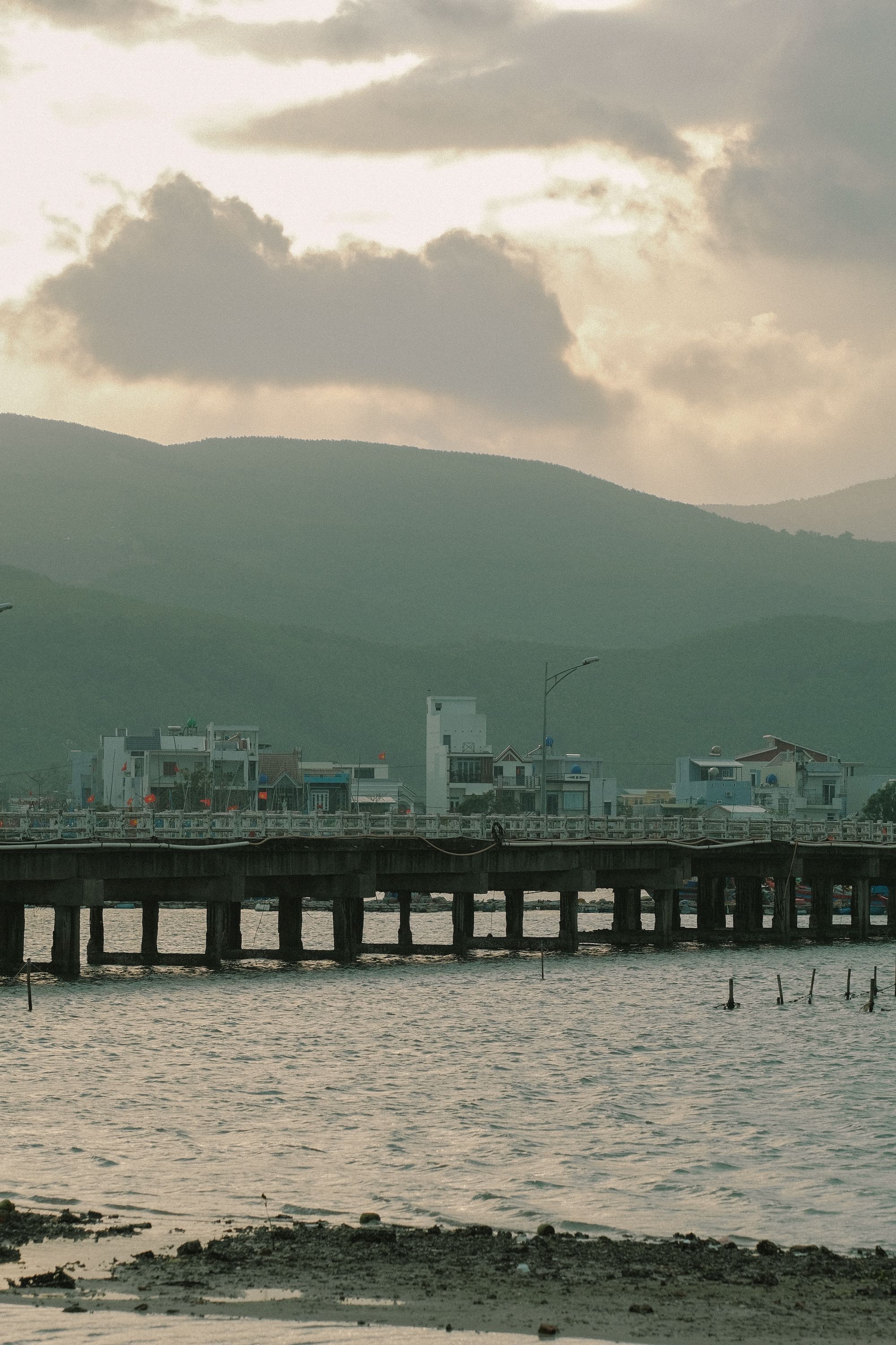 A bridge over a body of water with mountains in the background · Free ...