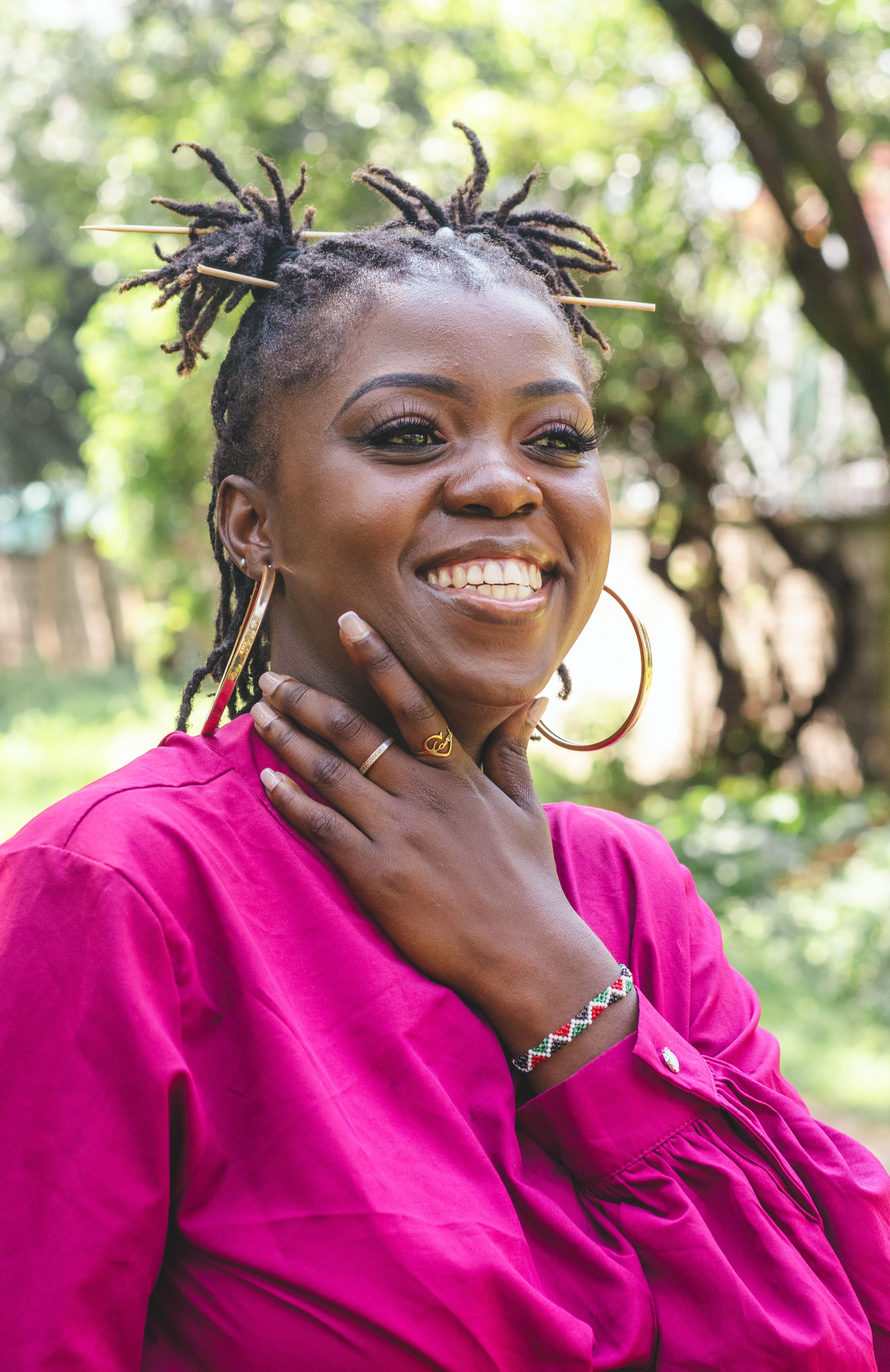 beautiful African woman in hoop earrings and maroon crop top smiling ...