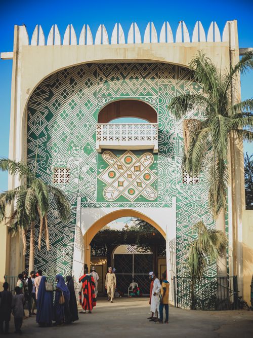 Free Colorful facade of traditional Nigerian architecture with geometric patterns and palm trees. Stock Photo