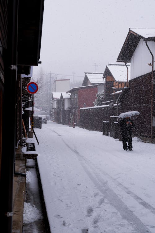 A person walking down a snowy street with an umbrella