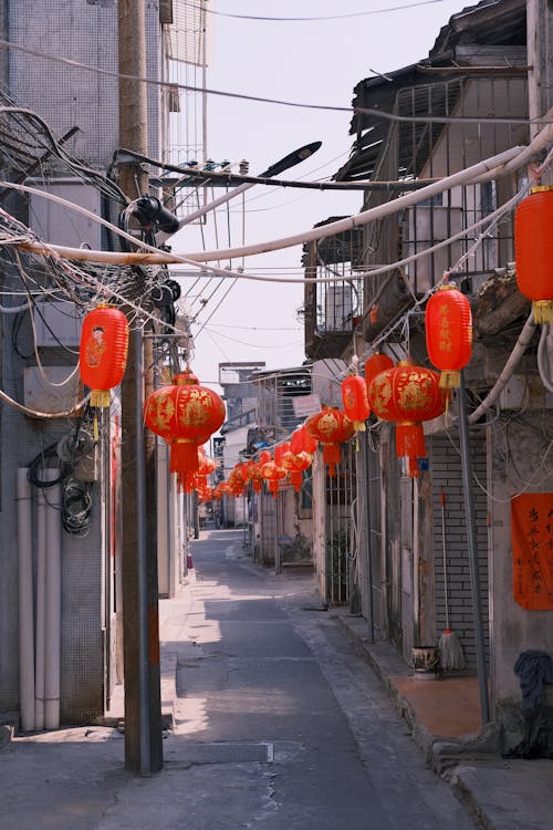 A narrow street with red lanterns hanging from the power lines