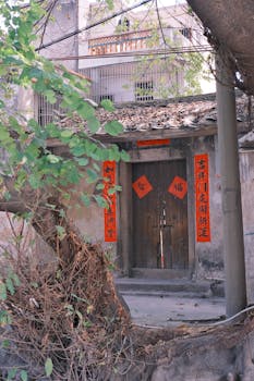 Rustic wooden doorway with red scrolls in a Taiwanese village setting.