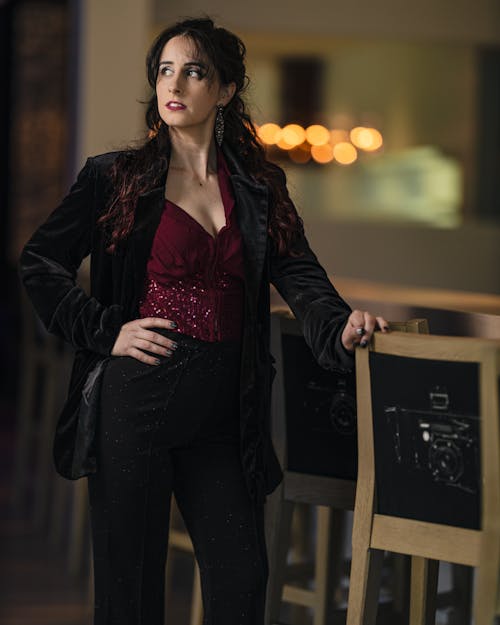 A woman in a black velvet jacket and red pants