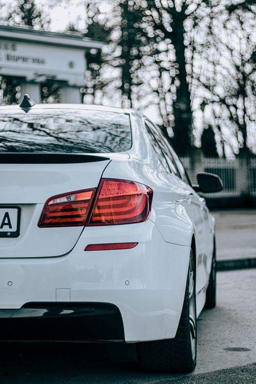 Free Close-up of a stylish white car showcasing its rear design and prominent red taillight. Stock Photo