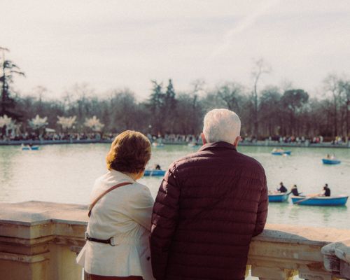 Free Elderly couple enjoying a peaceful view of boats on a park pond. Stock Photo