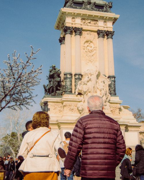 Free Elderly couple holding hands near a historical monument in Madrid's Retiro Park, Spain. Stock Photo