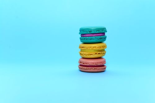 Free A vibrant stack of colorful macarons against a solid blue background, perfect for food photography and design. Stock Photo