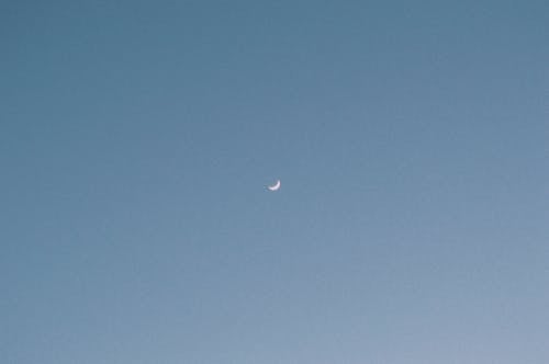 A crescent moon in the sky above a beach