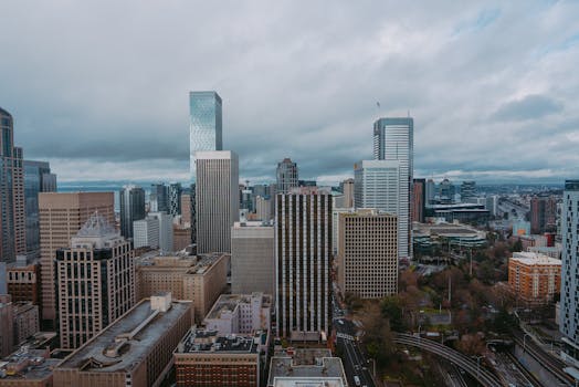 Aerial view of a modern city skyline on a cloudy day, showcasing skyscrapers and urban architecture.